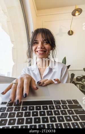 Giovane donna che guarda lo schermo di un notebook che guarda le informazioni. Foto Stock