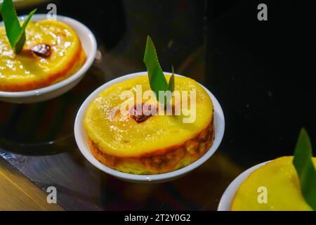 Serve il "Kue Lumpur" su un piatto di ceramica bianca adornato con foglie di panda e un pezzo centrale di contorno dell'uva passa Foto Stock