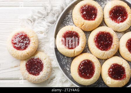 Anteprima dei biscotti con marmellata di lamponi svedesi Hallongrottor sul piatto del tavolo di legno bianco. Vista superiore orizzontale dall'alto Foto Stock