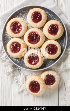 I classici biscotti con impronte digitali sono realizzati con un semplice impasto di biscotti zuccherati, quindi rifiniti e riempiti con marmellata di lamponi in primo piano sul piatto bianco Foto Stock