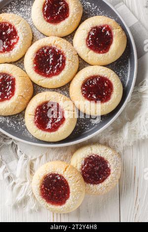 Deliziosi biscotti frolla farciti con marmellata di lamponi in primo piano sul piatto sul tavolo di legno bianco. Vista dall'alto verticale Foto Stock