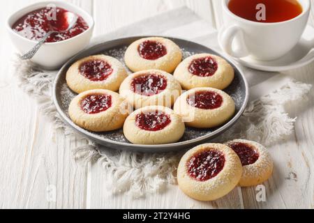 Anteprima dei biscotti con marmellata di lamponi svedesi Hallongrottor sul piatto del tavolo di legno bianco. Orizzontale Foto Stock