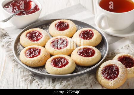 Primo piano dei biscotti di marmellata delle grotte di Hallongrottor o di rapsberry svedesi sul piatto sul tavolo di legno bianco. Orizzontale Foto Stock