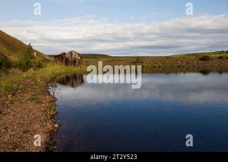 Una rovina di una baracca ai margini di un lago in Scozia in una soleggiata mattinata estiva durante una mattinata estiva Foto Stock