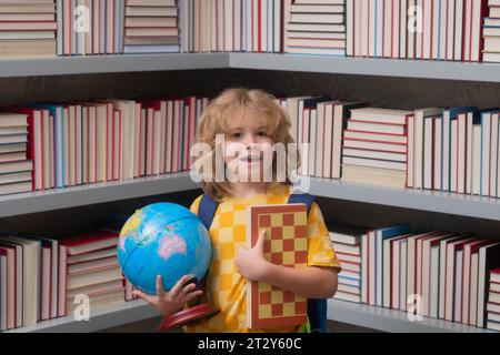 Ragazzo scolastico con globo mondiale e scacchi, infanzia. Torna a scuola. Bambino divertente della scuola elementare con il libro. Istruzione. I bambini studiano e. Foto Stock