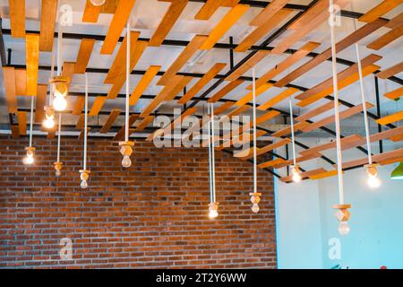 Modello di lampada a sospensione semplice ma accattivante disposto in modo ordinato su uno sfondo dall'affascinante design del tetto per una casa con pavimento in cemento. Elegante sistema di illuminazione Foto Stock