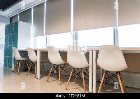 Interni di uffici. Sedie bianche meticolosamente disposte su una scrivania elegante e accogliente Foto Stock