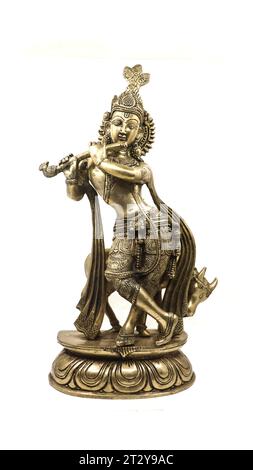 statua dorata del signore krishna realizzata con dettagli, un avatar di vishnu, che suona flauto vicino a una mucca in posizione danzante, vista frontale isolata Foto Stock