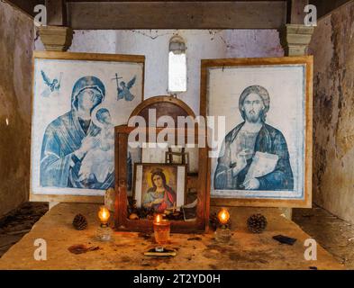 Icone cristiane su candele accese sull'altare di Agia Ekaterini, un monastero abbandonato e in rovina sulla costa settentrionale di Corfù in Grecia Foto Stock