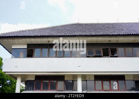 Vista chiara della sezione deteriorata di un vecchio edificio, che mostra una fila di finestre vecchie e danneggiate e vetri frantumati Foto Stock