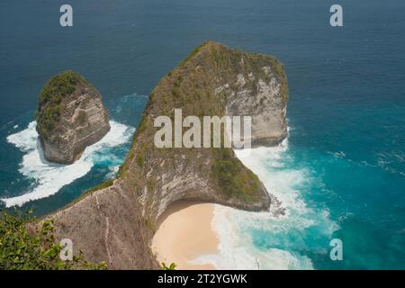 Scopri l'ampia bellezza di Kelingking Beach in questa vista panoramica, dove le acque schiumose accarezzano dolcemente la costa sabbiosa. Foto Stock