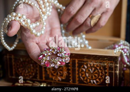 Scrigno di legno con oggetti di valore. Una donna tiene in mano perle, collane e altri gioielli. Foto Stock