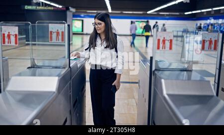 Giovane bella donna ispanica che controlla il biglietto al casello della metropolitana nella stazione della metropolitana di Madrid Foto Stock