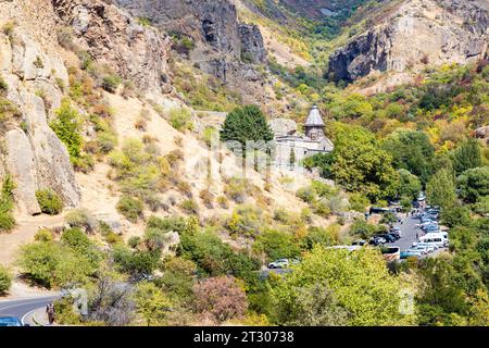 Goght, Armenia - 30 settembre 2023: Strada con auto parcheggiate vicino al Monastero di Geghard nell'alta Valle di Azat in soleggiato giorno autunnale. Geghard è elencato come ONU Foto Stock