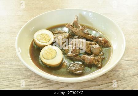 Uovo tagliato a metà bollito con carne d'anatra brasata e piede in zuppa marrone alle erbe cinesi su piatto Foto Stock