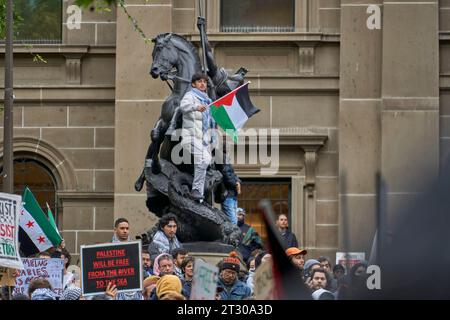 22 ottobre 2023, Melbourne, Victoria, Australia. La Statua di San Giorgio che posa un drago presso la Biblioteca di Stato di Victoria e un sostegno pro Palestina con una bandiera palestinese, ascoltando i discorsi. Foto Stock