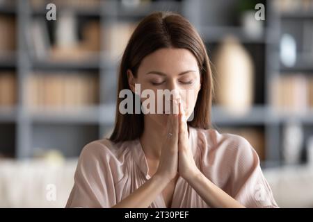 Una donna fedele piegò i palmi insieme pregando Dio Foto Stock