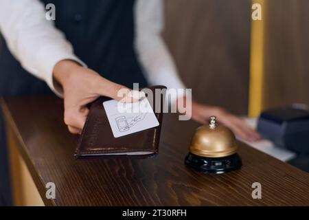 Primo piano dell'addetto alla reception che dà il passaporto e la chiave dalla camera dell'hotel Foto Stock