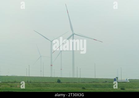 Turbine eoliche in piedi lungo la strada nella nebbia. Concetto di energia rinnovabile. Foto Stock