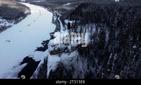 Epica scena aerea cinematografica di un gruppo di sciatori ed escursionisti sulla cima di una montagna. Clip. Inverno sulla cima della scogliera sullo sfondo del fiume ghiacciato Foto Stock