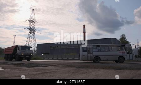 Serbia - Belgrado, 20 maggio 2023: Paesaggio industriale di una piccola città con trasporto pubblico e camino della fabbrica. Clip. Autobus e camion in movimento Foto Stock