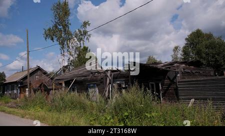 Bruciato casa di legno abbandonata. Clip. Paesaggio estivo del villaggio con cielo nuvoloso blu. Foto Stock