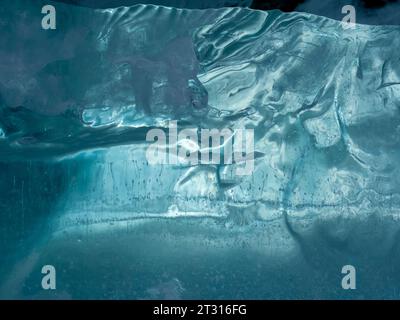 Consistenza di ghiaccio ghiacciato di un lago di montagna. Spessore del ghiaccio verde-blu attraverso il quale è visibile la luce Foto Stock