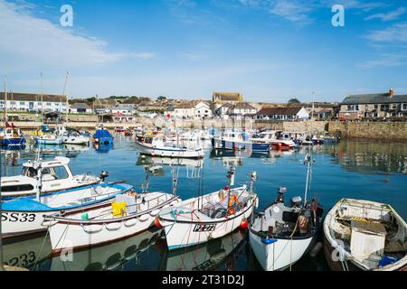 Porthleven, Regno Unito - 9 ottobre 2023 barche da pesca e da diporto nel porto con il villaggio sullo sfondo in una calda giornata di ottobre. Foto Stock