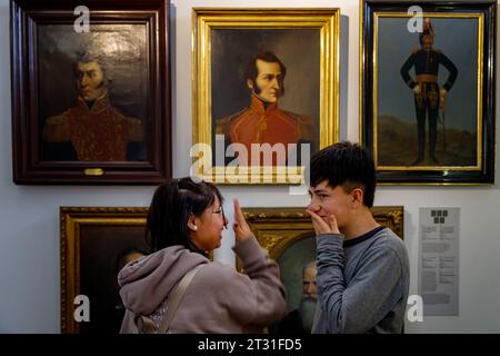 Bogotà, Colombia - 8 gennaio 2023: Due adolescenti ridono di fronte ai ritratti dipinti di eroi colombiani nel Museo Nazionale Foto Stock