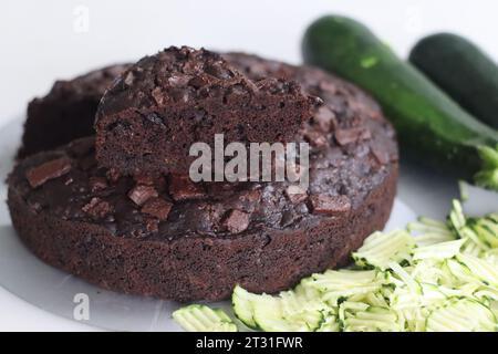 Fetta di torta al cioccolato zucchine sulla torta rotonda. Torta al cioccolato doppia umida con zucchine grattugiate, polvere di cocco, cioccolato e goccia di cioccolato Foto Stock