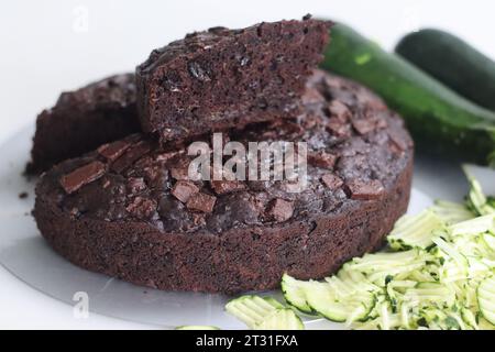 Fetta di torta al cioccolato zucchine sulla torta rotonda. Torta al cioccolato doppia umida con zucchine grattugiate, polvere di cocco, cioccolato e goccia di cioccolato Foto Stock