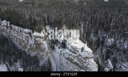 Vista dall'alto di un gruppo di persone sulla scogliera in inverno. Clip. Splendido paesaggio con scogliere di montagna e una folla di persone ai margini. Paesaggio invernale con Foto Stock