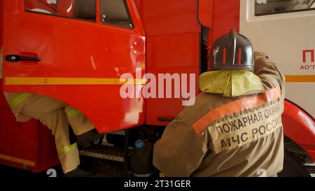 I vigili del fuoco salgono in macchina. Clip. I vigili del fuoco entrano in macchina e vanno a chiamare. I vigili del fuoco si stanno preparando e vanno fuori di guardia Foto Stock