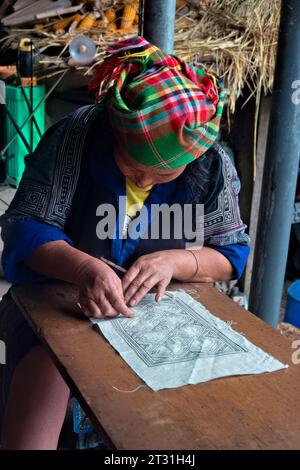 Una donna Flower Hmong disegna un modello per il suo ricamo tradizionale, Mu Cang Chai, Yen Bai, Vietnam Foto Stock