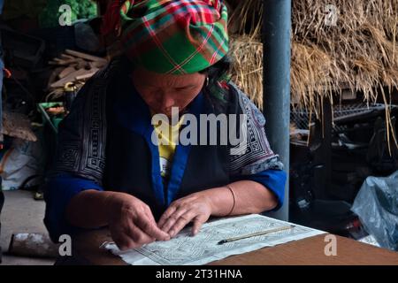 Una donna Flower Hmong disegna un modello per il suo ricamo tradizionale, Mu Cang Chai, Yen Bai, Vietnam Foto Stock