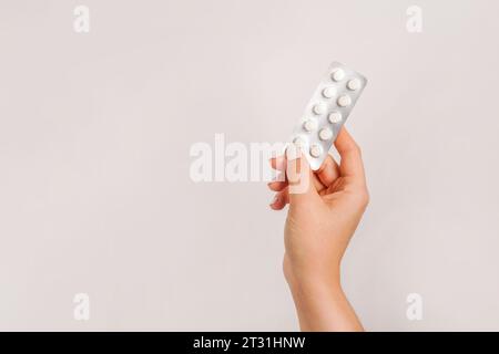 Mano che tiene pillole mediche su sfondo grigio chiaro. copia spazio Foto Stock