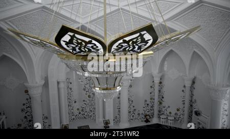 A very expensive chandelier in a chic hall. Scene. White beautiful interior of an empty concert or restaurant hall. Foto Stock