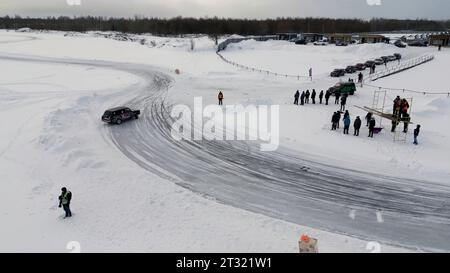 Vista dall'alto delle corse automobilistiche invernali. Clip. Auto da corsa in pista nei campi invernali. Gare automobilistiche su strada in inverno Foto Stock