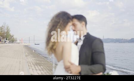 Bella coppia innamorata abbraccia sull'argine. Azione. Elegante coppia in abiti durante la data sull'argine. Una bella coppia di amanti si abbracciano con tenerezza Foto Stock