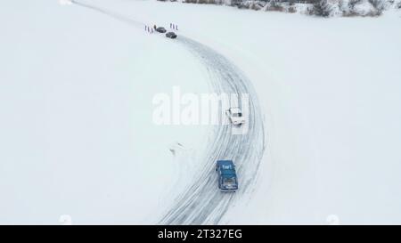 Vista aerea delle auto alla deriva sulla neve coperta fuori strada. Clip. Gara invernale su un lago ghiacciato. Foto Stock