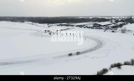 Rallentatore di un campionato di auto da corsa che scivola su una pista di ghiaccio. Clip. Gare invernali di drift, vista aerea. Foto Stock