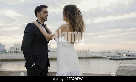 Giovane e bella coppia di nozze si trova vicino al fiume o al lago. Azione. Sposo e sposo adorabili il giorno del loro matrimonio. Foto Stock