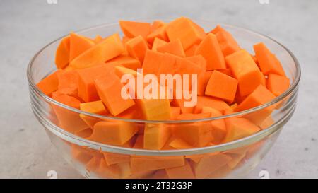 Ricetta per zuppa di zucca. Cubi di una zucca da vicino in una ciotola sul tavolo della cucina Foto Stock