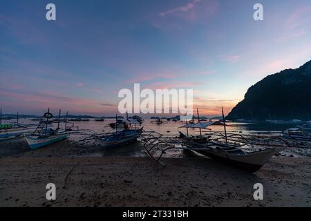 Paradiso tropicale sulla spiaggia dopo il tramonto con tradizionali battelli banca filippini con spiaggie e bilancieri Foto Stock