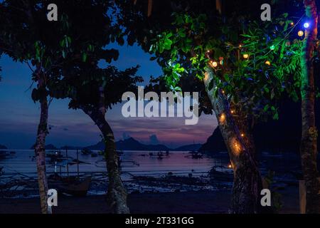 Tradizionali battelli filippini banca con balenieri ancorati al largo di notte in un paradiso tropicale Foto Stock