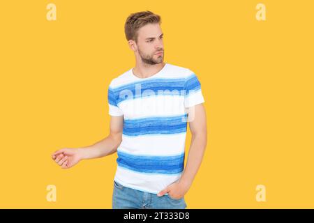 elegante modello uomo in stile estivo. uomo che indossa un outfit estivo. Un uomo mostra il suo stile estivo in una maglietta isolata sul giallo. Un'estate da uomo Foto Stock