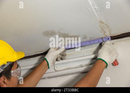 Il lavoratore ripara il tubo che perde nel soffitto, primo piano di una macchia sul soffitto. Foto Stock