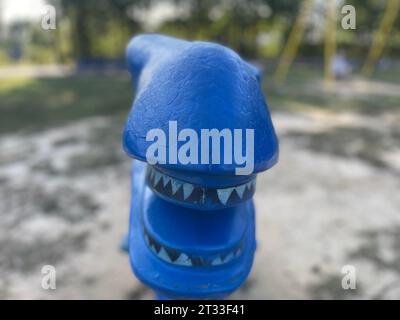 giro per bambini con la testa di dinosauro blu su sfondo primaverile Foto Stock