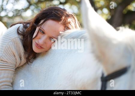 La natura, il sorriso e la donna che poggia sul suo cavallo in una fattoria all'aperto per le corse sportive. Amore, felice e giovane dal Canada con il suo animale equestre Foto Stock