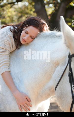 Natura, amore e donna che sdraiano a cavallo in una fattoria all'aperto per le corse sportive. Sorridi, felice e giovane proveniente dal Canada con il suo animale equestre Foto Stock